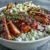 Savory BBQ Chicken Bowl featuring tender chicken, white rice, crunchy slaw, and roasted red peppers and zucchini.