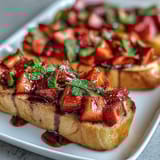 Fresh strawberry bruschetta with balsamic glaze and mint on toasted baguette slices, perfect for summer entertaining or a light snack.