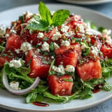Vibrant watermelon feta arugula salad with glossy balsamic reduction, perfect for summer.