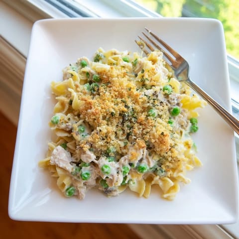 Spoon a hearty serving of Tuna Casserole onto a plate, showcasing flaky tuna and melted cheddar in every bite. 