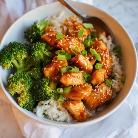 Overhead view of Sweet Chili Chicken Bowl featuring glossy sweet chili sauce drizzled over juicy chicken and crisp broccoli florets.  