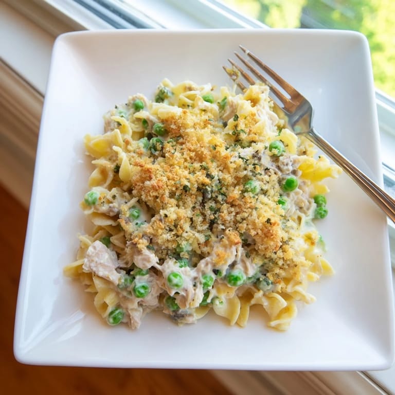 Spoon a hearty serving of Tuna Casserole onto a plate, showcasing flaky tuna and melted cheddar in every bite. 