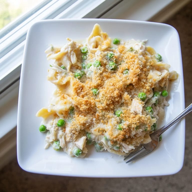 Comforting Tuna Casserole sits beside a crisp green salad and chilled white wine for a perfect family dinner.
