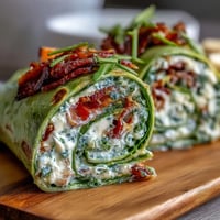 Colorful spinach pinwheel wraps filled with herb cream cheese, fresh veggies, and crisp greens—ideal for healthy snacking.