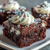 Fourth of July Firecracker Brownie Bites with creamy frosting and red, white, and blue sprinkles on a festive platter.